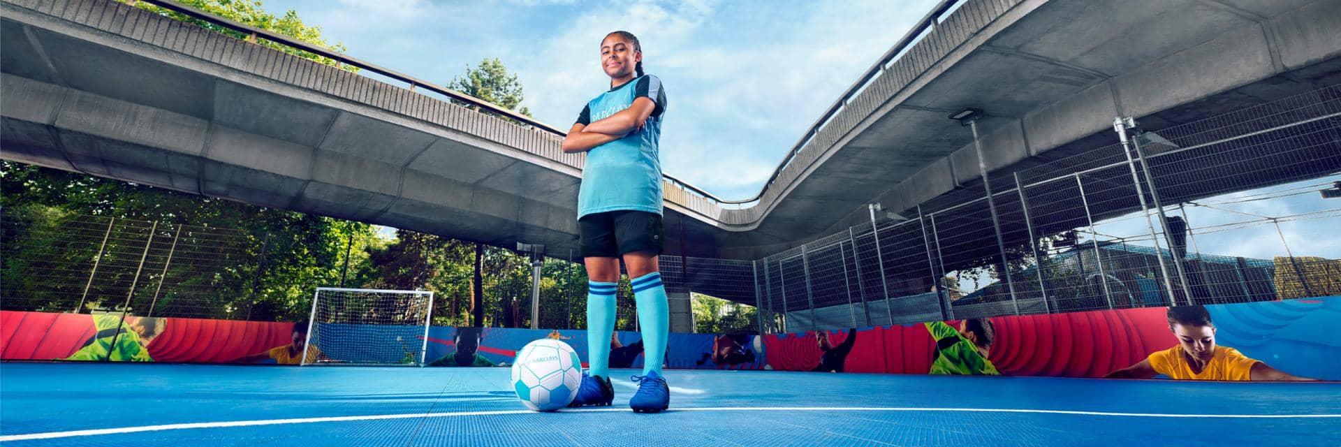 A girl in a bright blue football kit looking down to camera